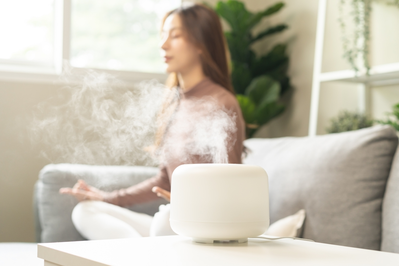 woman meditating next to essential oil diffuser